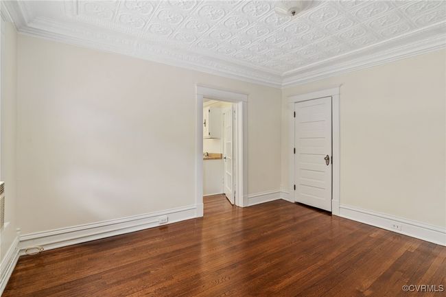Bedroom with wood finished floors, baseboards, an ornate ceiling, and crown molding | Image 31
