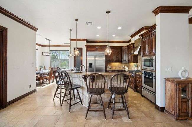 Kitchen with a warming drawer, visible vents, backsplash, stainless steel appliances, and wall chimney range hood | Image 15