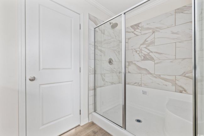 Full bath featuring a stall shower, crown molding, and wood finished floors | Image 29