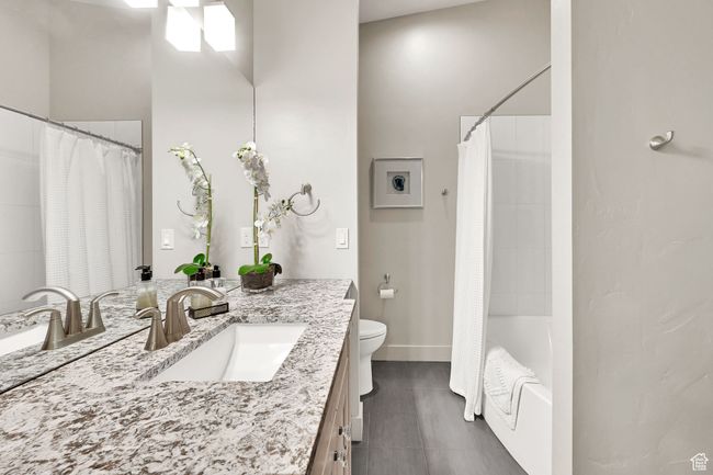 Bathroom with vanity, toilet, tile patterned floors, shower / bath combo, and baseboards | Image 54