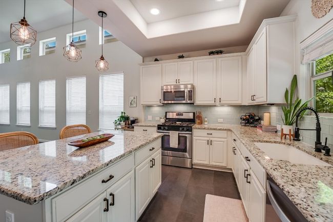 Kitchen with stainless steel appliances, a sink, white cabinetry, decorative backsplash, and recessed lighting | Image 15