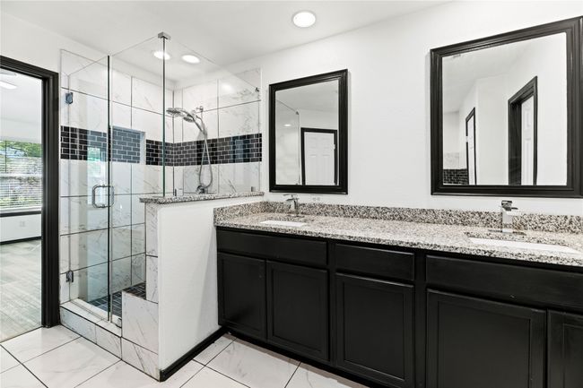 Primary bathroom features a modern shower, separate soaking tub, and his/hers walk-in closets. | Image 16