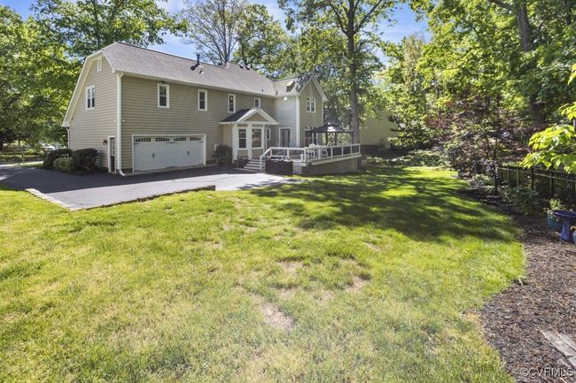 Back of property featuring an attached garage, a wooden deck, and a yard | Image 6