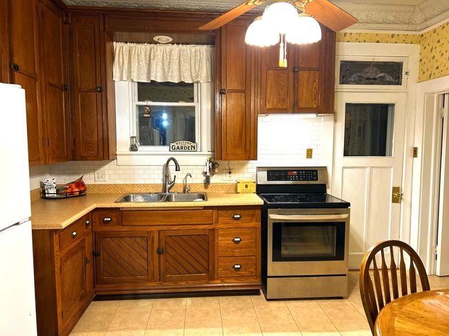Kitchen features stove and refrigerator and table area plus access to Enclosed Back Porch | Image 18