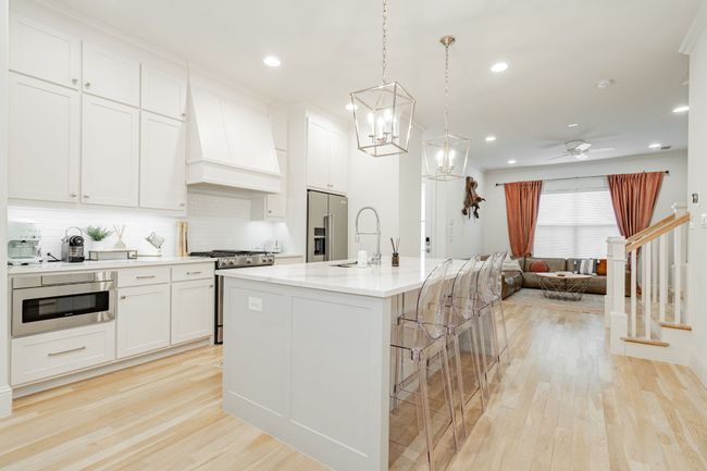 Kitchen featuring a sink, open floor plan, appliances with stainless steel finishes, premium range hood, and light wood-style flooring | Image 6