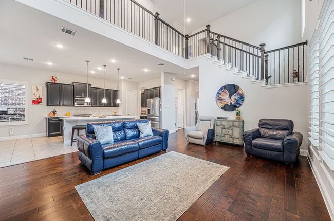 Living room featuring wood flooring, open-concept floorplan with wrought iron balusters all the way up to the second floor and overlooking living room. | Image 16