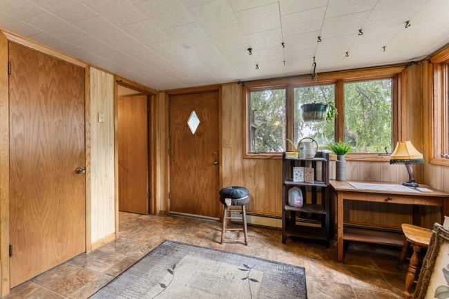 The lower level extends your living space with a generous family room featuring warm wood walls, durable tile flooring, a second wood-burning fireplace, and a ceiling fan. Walkout access to the backyard enhances the versatility of this area. | Image 9