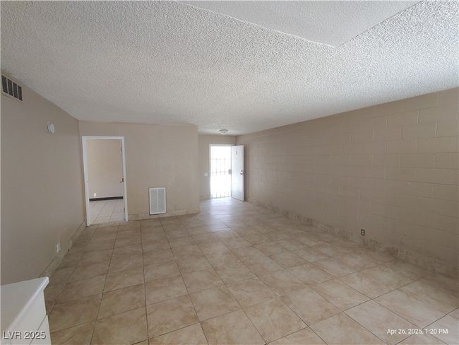 Unfurnished room featuring concrete block wall, a textured ceiling, and visible vents | Image 4