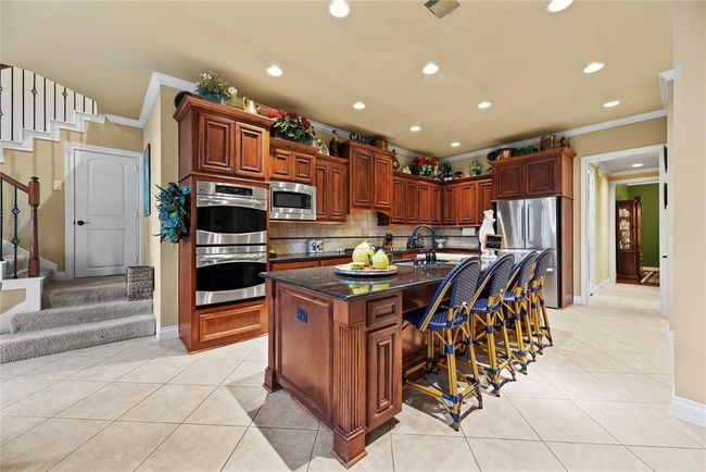 View of the kitchen from the breakfast area allows visibility of the island and wooden cabinets flanked by stainless steel appliances. | Image 8