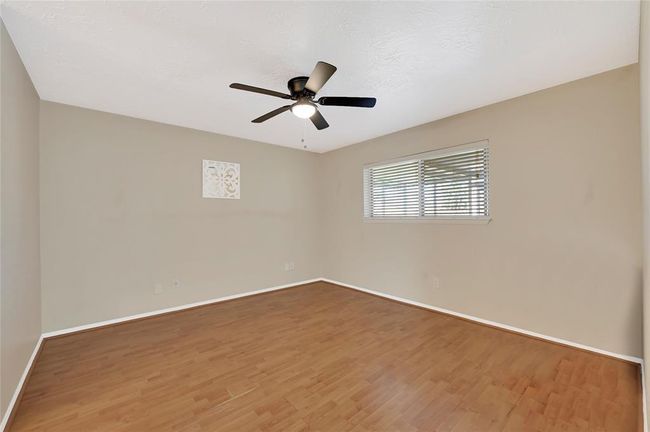 Spacious primary room with elegant flooring, abundant natural light, and a ceiling fan for comfort. | Image 19