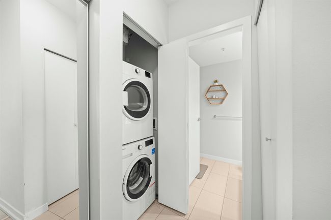 Laundry room with stacked washing machine and dryer and light tile patterned floors | Image 6