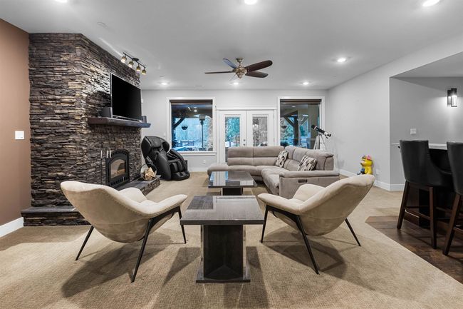 Living room featuring a stone fireplace, recessed lighting, a ceiling fan, baseboards, and french doors | Image 24