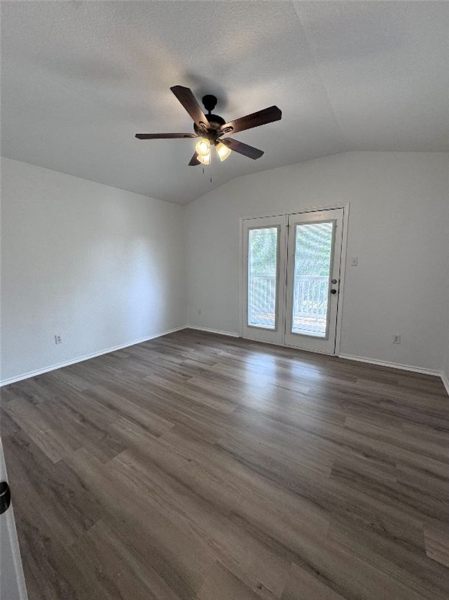 Empty room featuring a ceiling fan, lofted ceiling, and dark wood-style flooring | Image 29