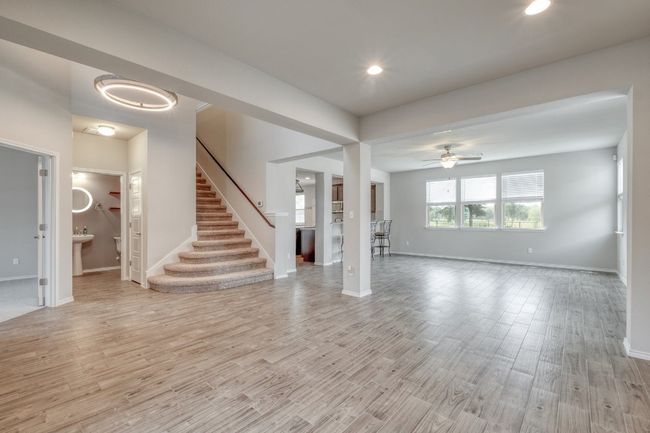 Unfurnished living room featuring light wood finished floors, stairs, a ceiling fan, and recessed lighting | Image 6