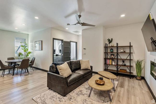 Living room with light wood finished floors, recessed lighting, visible vents, a glass covered fireplace, and baseboards | Image 30