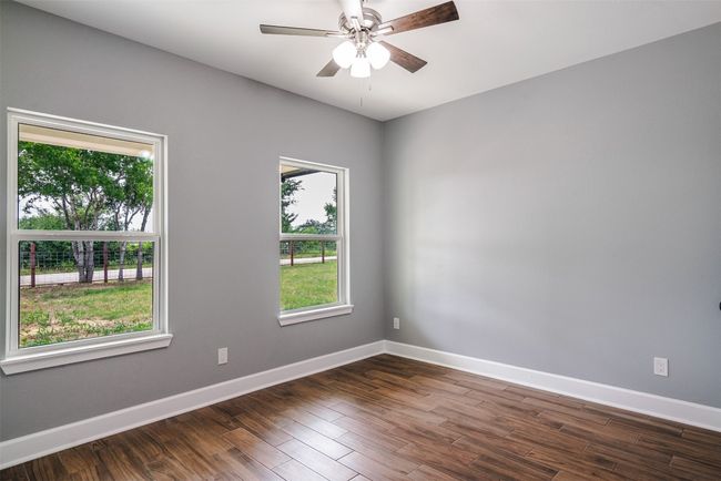 Unfurnished room with baseboards, ceiling fan, and dark wood-type flooring | Image 22