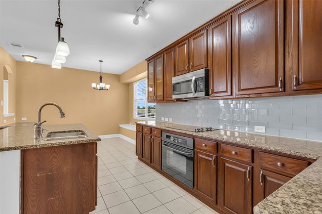 Kitchen featuring black appliances, light tile patterned floors, decorative backsplash, and decorative light fixtures | Image 7