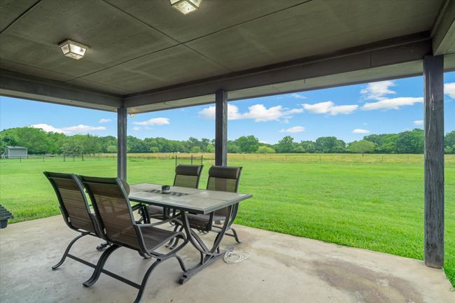 Covered patio overlooks a large backyard that backs up to a pasture | Image 28