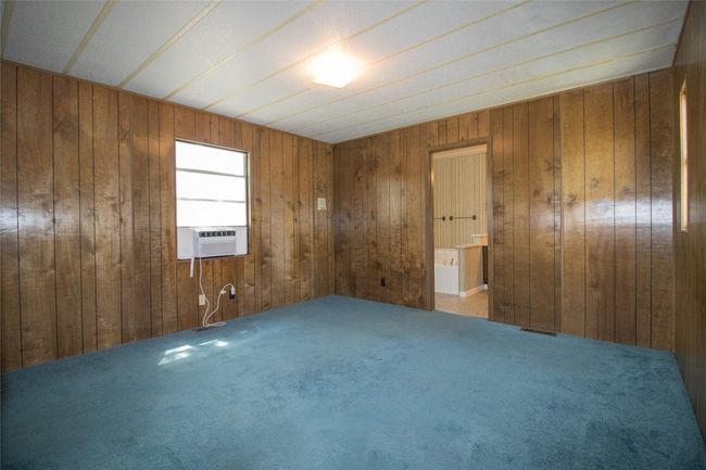 Carpeted spare room featuring cooling unit and wooden walls | Image 8