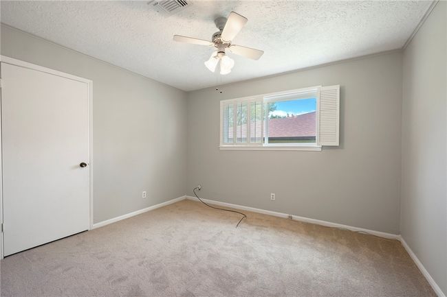 Carpeted empty room with a textured ceiling, a ceiling fan, and baseboards | Image 17