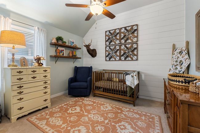 Bedroom with lofted ceiling, a crib, and light colored carpet | Image 23