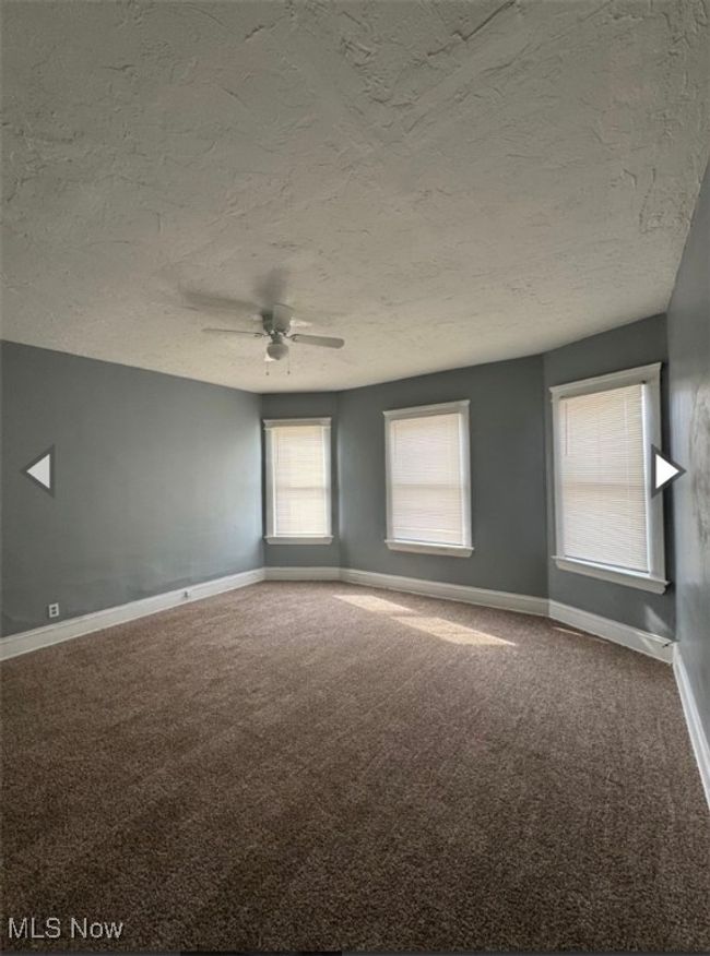 Carpeted empty room featuring ceiling fan and a textured ceiling | Image 4