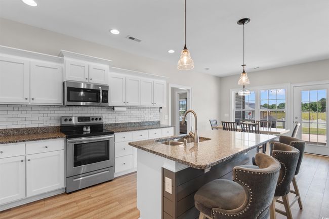 Kitchen featuring appliances with stainless steel finishes, light wood finished floors, backsplash, white cabinetry, and recessed lighting | Image 9