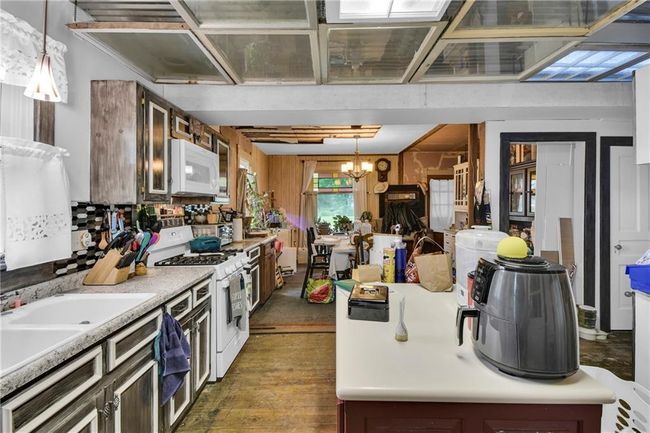 Kitchen with white appliances, light countertops, pendant lighting, a chandelier, and dark wood finished floors | Image 8