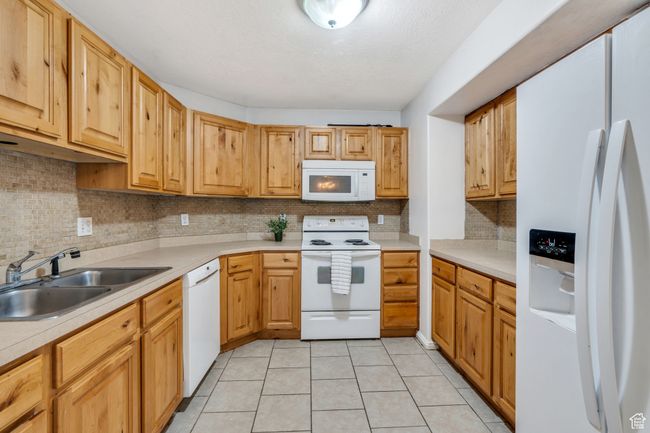 Kitchen featuring white appliances, light countertops, tasteful backsplash, and light tile patterned floors | Image 4