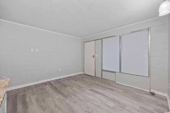 Unfurnished room with crown molding, wood finished floors, baseboards, and a textured ceiling | Image 8