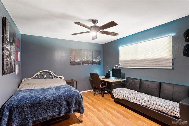 Bedroom with wood finished floors, a desk, and ceiling fan | Image 7
