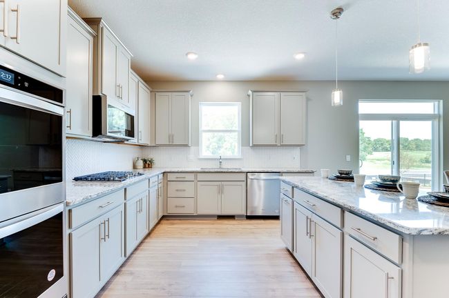 The kitchen of your dreams - complete with stunning Granite countertops, elegant backsplash, modern cabinetry & a stainless steal appliances that'll leave the family chef in their happy place! Photo of model home, color & options will vary. | Image 15