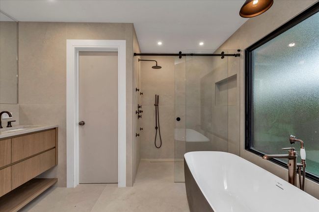 Bathroom with tiled shower, tile walls, vanity, a freestanding tub, and recessed lighting | Image 10