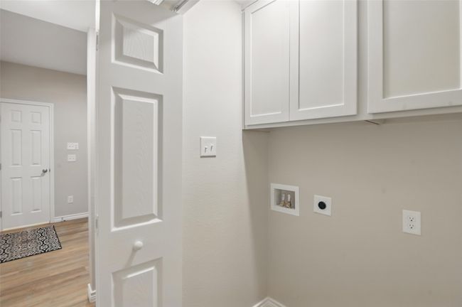 Laundry room featuring hookup for an electric dryer, baseboards, light wood-style flooring, cabinet space, and washer hookup | Image 10