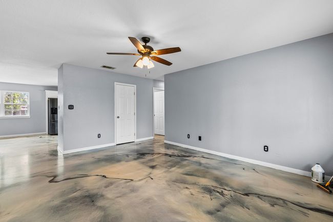 Unfurnished bedroom featuring concrete floors, stainless steel fridge, and a ceiling fan | Image 16