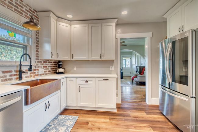 Kitchen with stainless steel appliances, arched walkways, pendant lighting, white cabinetry, and light wood finished floors | Image 7