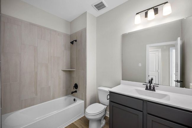 Step into the secondary bathroom, where a sleek vanity and mirror create a polished look, and the tub-shower combo ensures versatility for bathing preferences. With its thoughtful design and efficient layout, this bathroom offers both functionality and comfort. | Image 8
