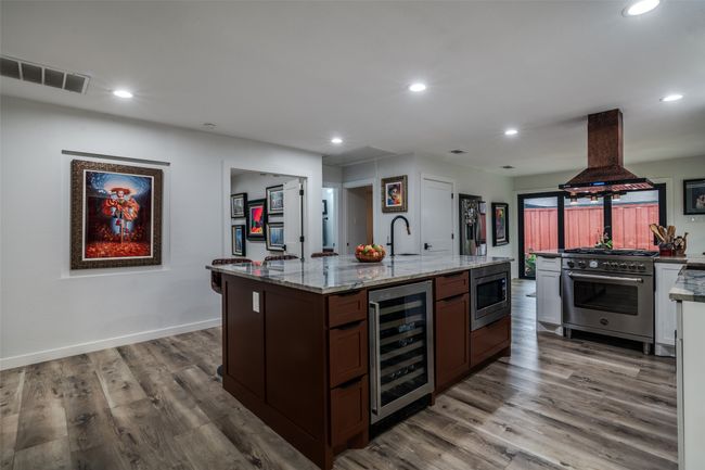 Kitchen featuring wine cooler, appliances with stainless steel finishes, island range hood, wood finished floors, and recessed lighting | Image 10