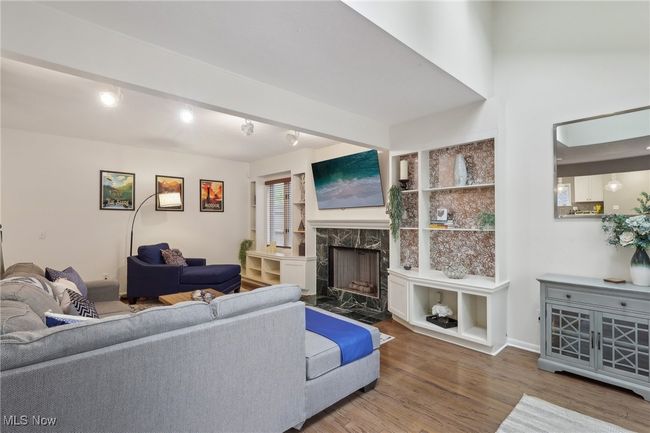 Living room with baseboards, wood finished floors, and a fireplace | Image 11