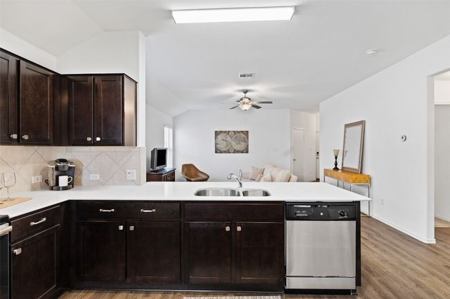 Kitchen featuring dishwasher, a peninsula, vaulted ceiling, light countertops, and open floor plan | Image 11