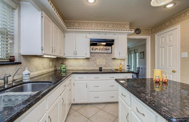 Timeless granite with tumbled marble backsplash and clean line cabinets. | Image 13