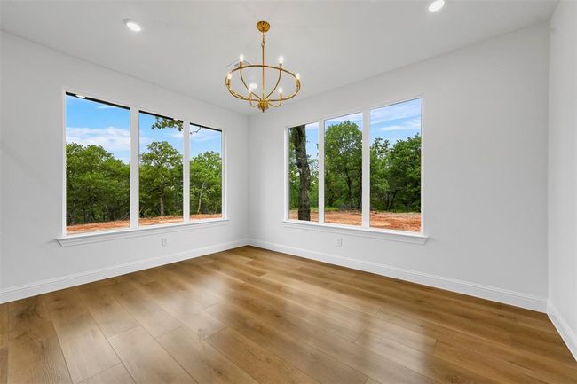 Unfurnished room featuring hardwood / wood-style floors, a wealth of natural light, and a notable chandelier | Image 22