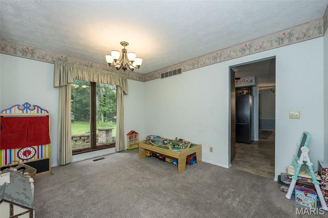 Playroom with a chandelier, carpet, a textured ceiling, and baseboards | Image 8