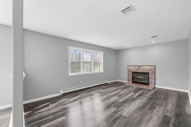 Unfurnished living room with visible vents, baseboard heating, wood finished floors, and baseboards | Image 10
