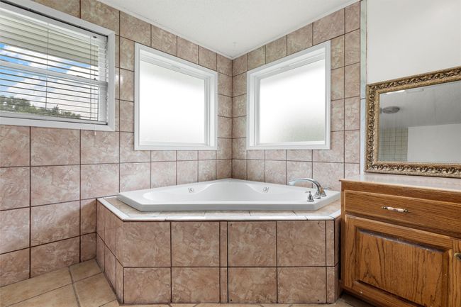 Full bath with a garden tub, healthy amount of natural light, tile walls, and vanity | Image 20