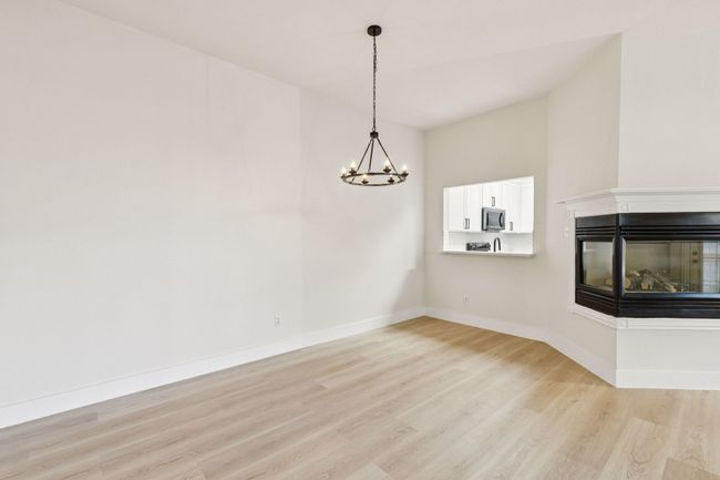 Unfurnished dining area with a chandelier, light wood-type flooring, and a multi sided fireplace | Image 9