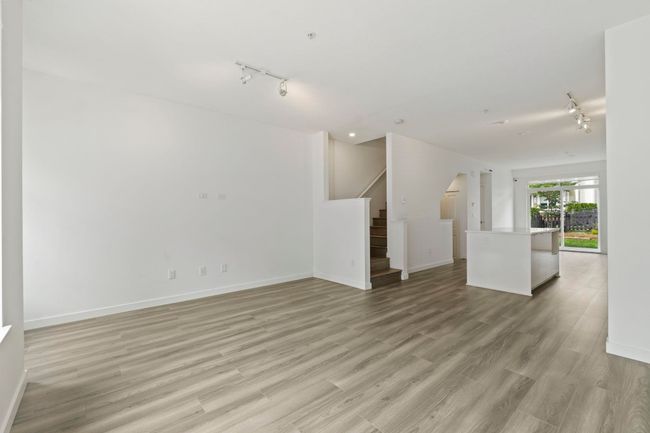 Unfurnished living room with rail lighting, stairs, and light wood finished floors | Image 6