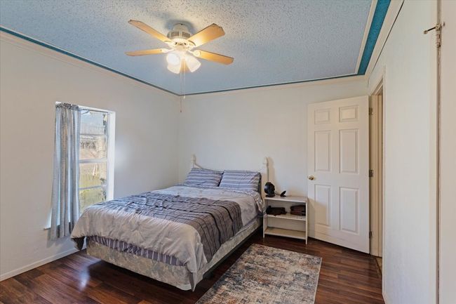 Bedroom with ceiling fan, dark wood-type flooring, ornamental molding, and a textured ceiling | Image 18