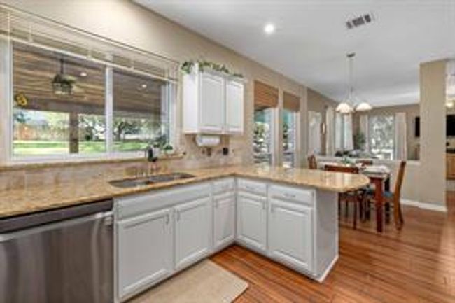 Kitchen with light wood finished floors, a peninsula, a sink, pendant lighting, and dishwasher | Image 18