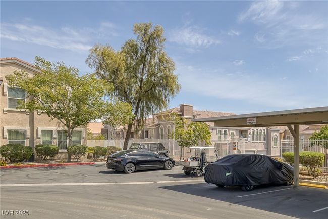 Partially covered parking lot featuring a residential view and fence | Image 25